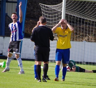 Rory Coleman reacts in disbelief at the penalty award, while Lee Bennett calls the Shaw Lane physio on