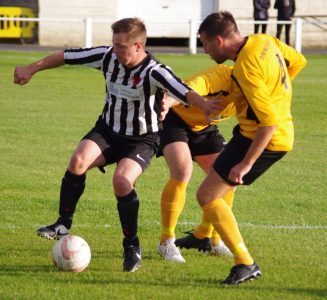 Penistone striker Steven Kenworthy attempts to win a battle with two Handsworth players