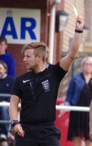 Stocksbridge-based referee Lee Hible shows a yellow card during Hemsworth's 3-0 win over Garforth