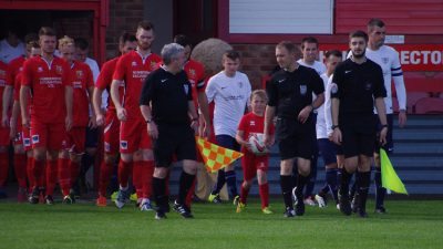 Referee Matthew Bacon leads the teams out